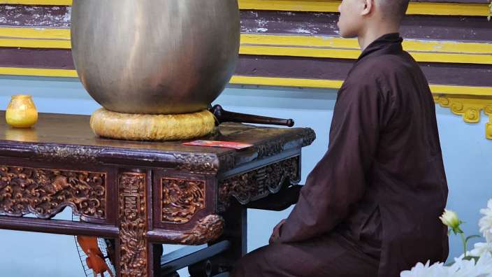 Mönch vor Klangschale in der Pagode in Hue